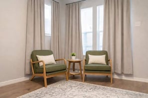 A room with two green armchairs, a small round table with a plant, and a patterned rug. - Fort Worth 3BR • King Bed • Near TCU & Downtown (Fort Worth)