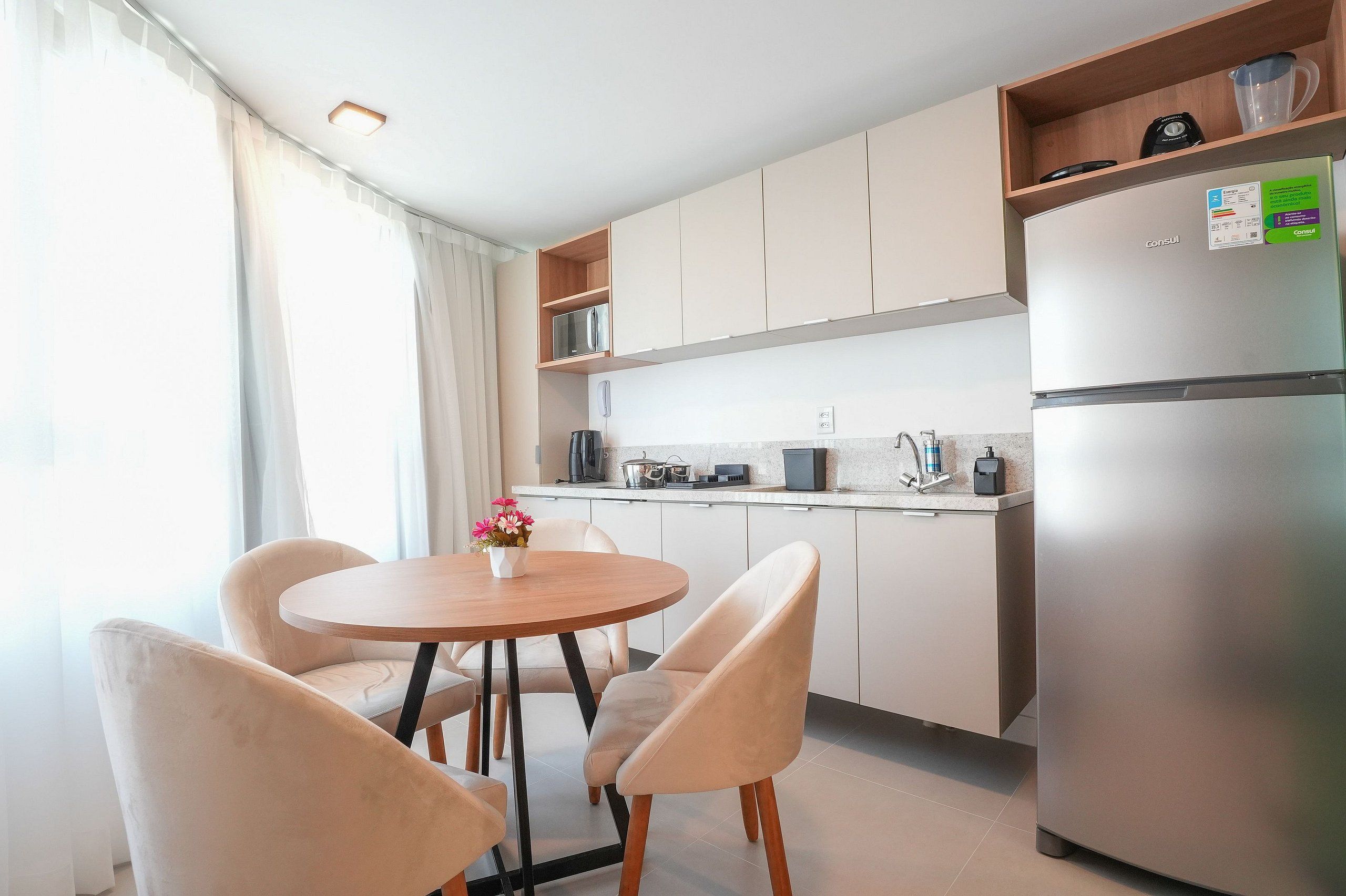 Une cuisine moderne équipée d’un réfrigérateur, d’une machine à café et d’un évier. On y trouve également une table à manger avec des chaises.