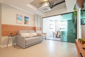 A modern living room with a sofa, a small side table, and a glass door leading to a dining area. - Silo 215 in Recife Antigo With Two Leisure Rooftops, Pools, Gym, Coworking and Sea View, Near Marco Zero by Carpediem (Recife)