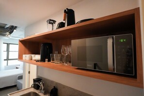 Cozinha equipada com micro-ondas, máquina de café e uma estante com copos de vinho.
