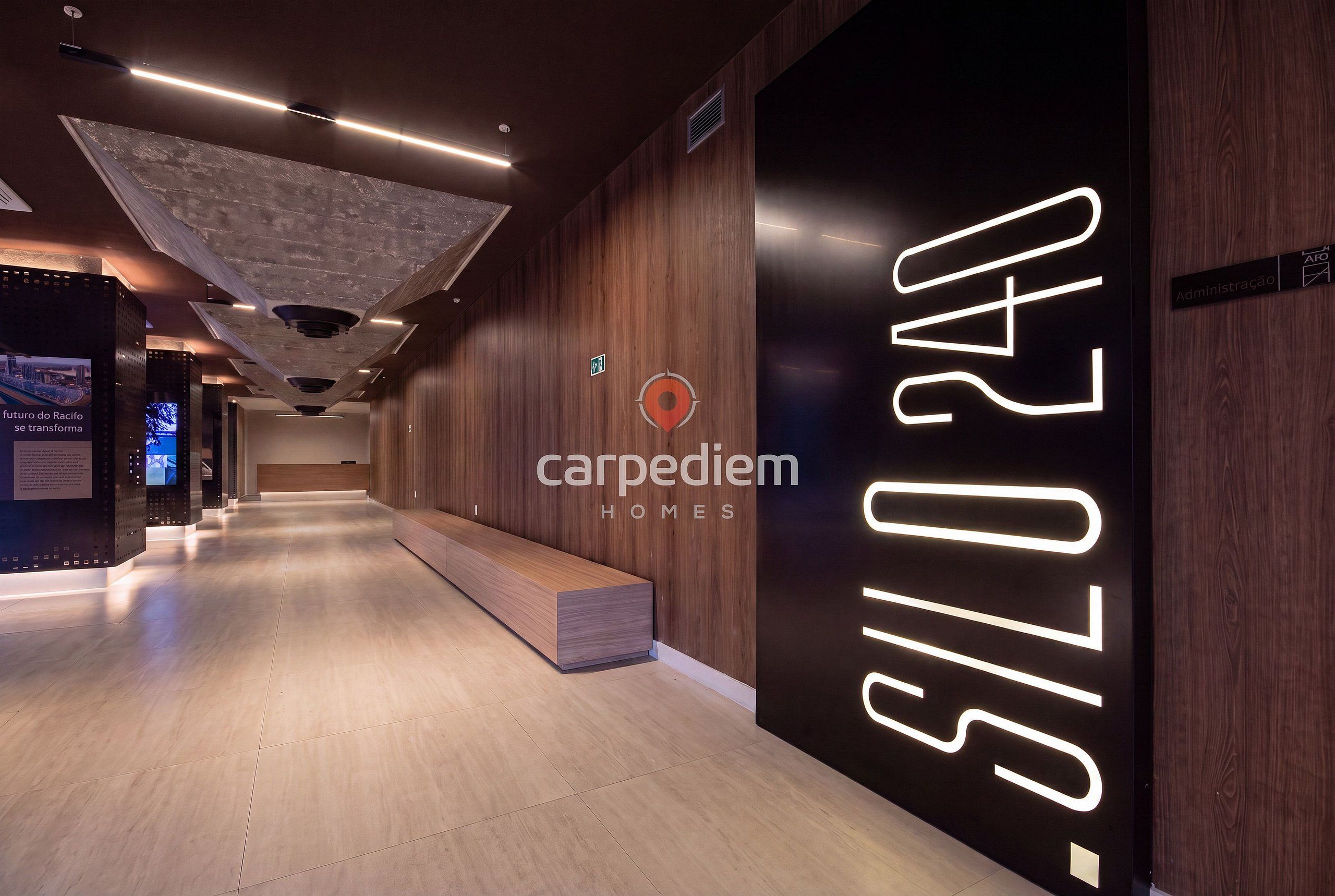 A modern interior with a reception desk, wooden paneling, and a large illuminated sign reading 'carpediem homes'.