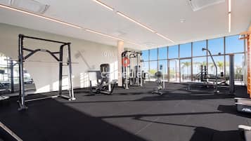 A gym with various exercise equipment, large windows, and a modern design.
