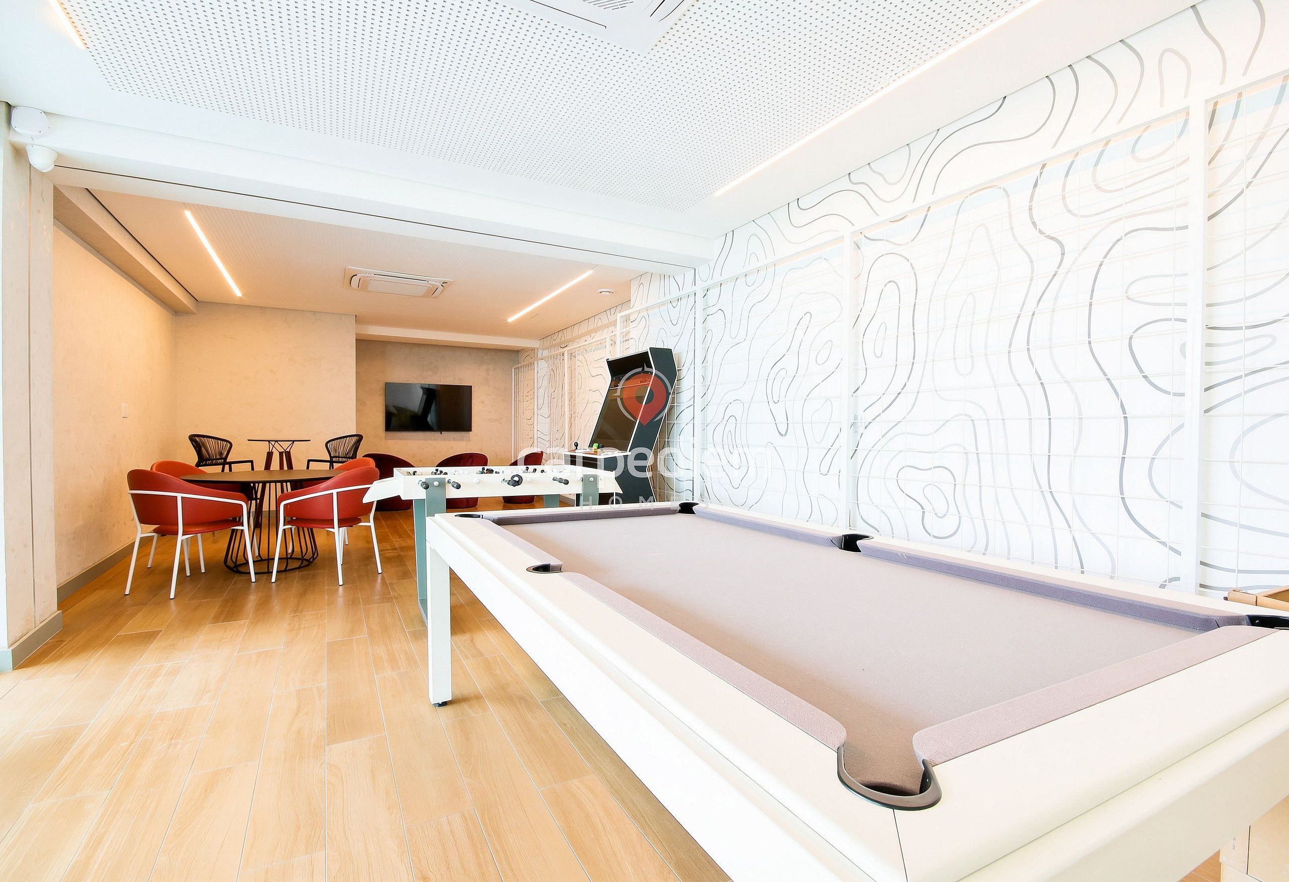 A billiards table with a pool table, a dining area with chairs and a table, and a patterned wall.