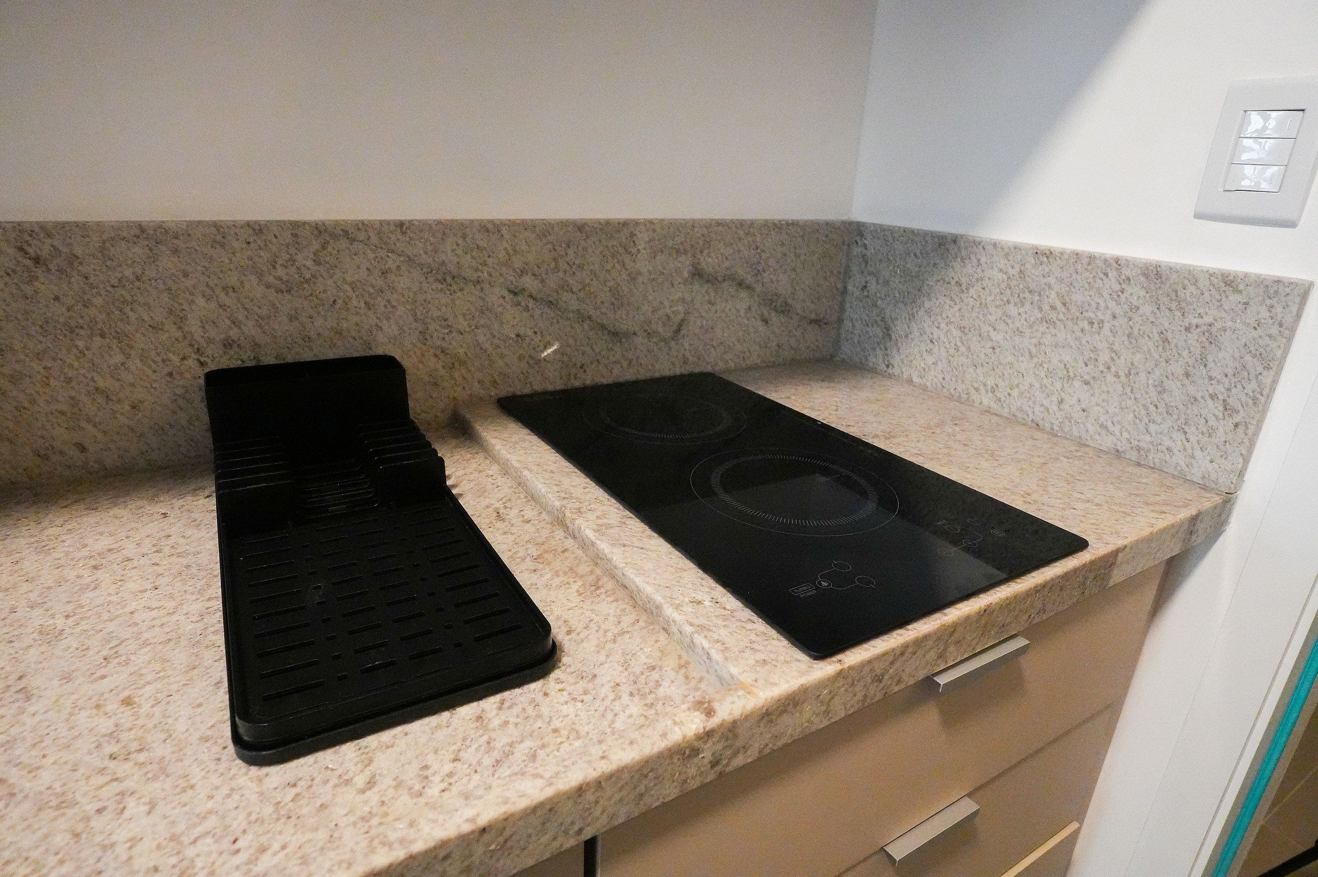 A kitchen with a granite countertop, a black induction cooktop, and a black electric stove.