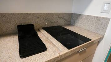 A kitchen with a granite countertop, a black induction cooktop, and a black electric stove.