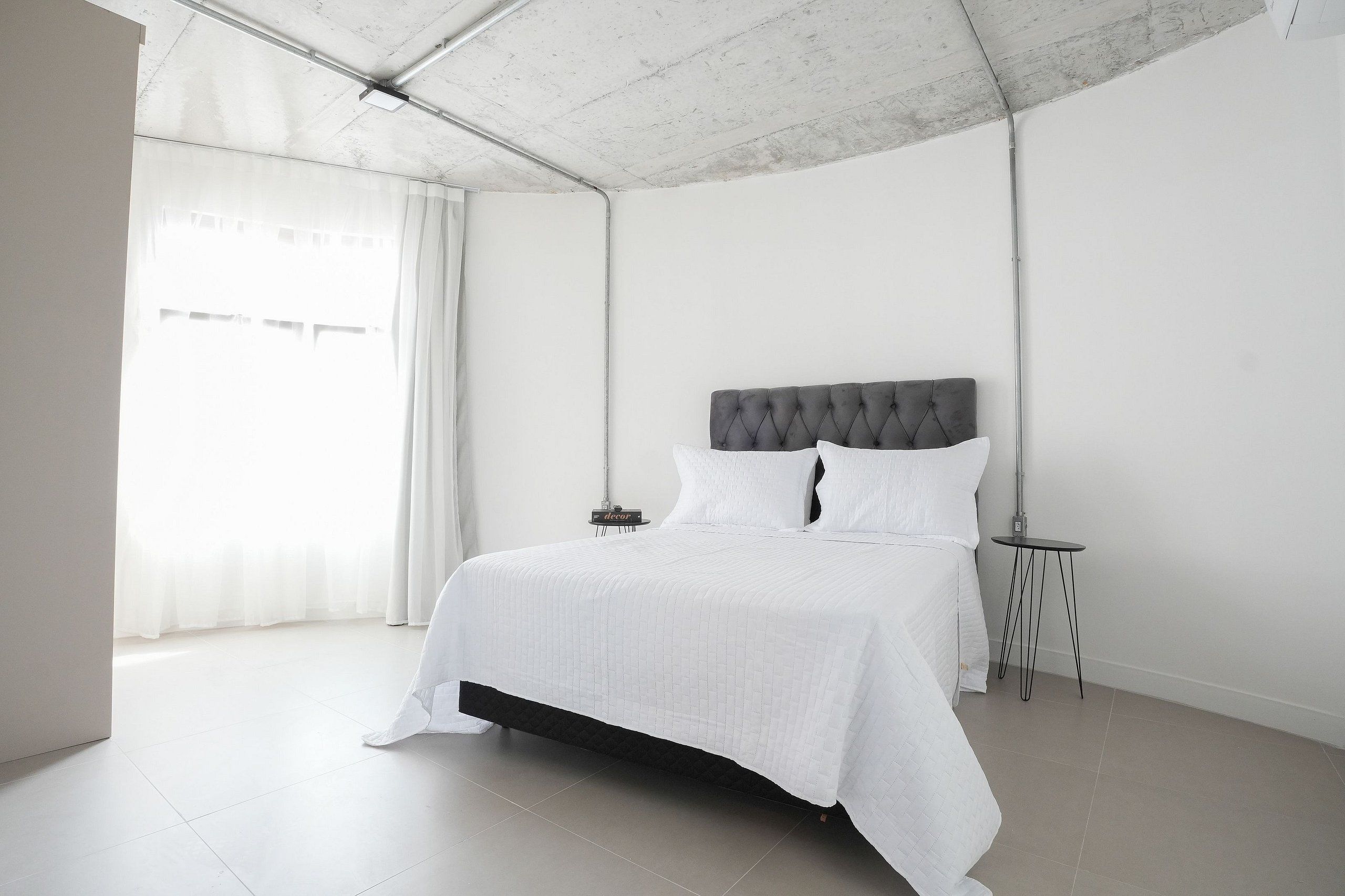 A minimalist bedroom with a large bed, a bedside table, and a modern light fixture.