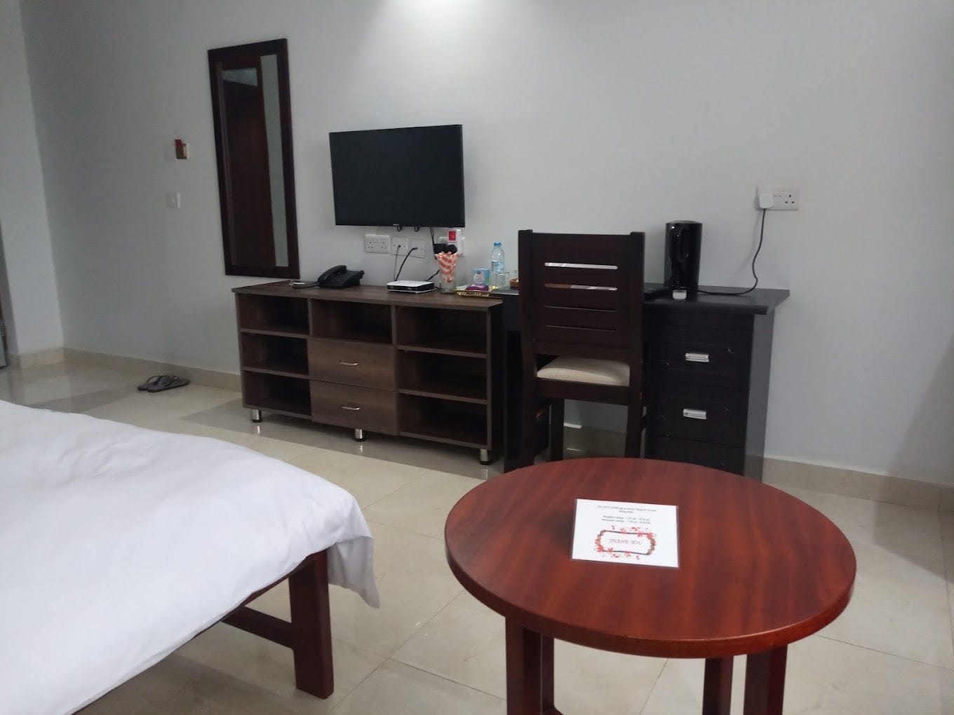 Una habitación de hotel con cama, escritorio con computadora, silla y una mesita.