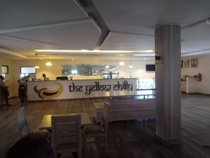 Interior de un restaurante con mostrador, sillas y un cartel de menú visible.