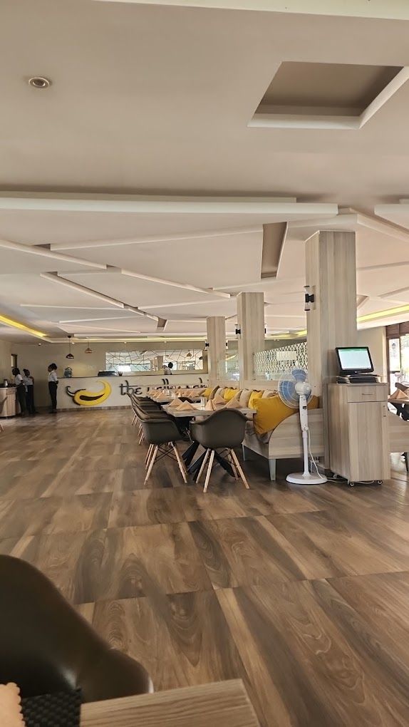 Un interior de restaurante con una larga mesa de comedor, sillas y una zona de barra.