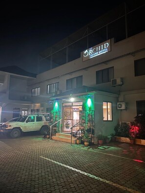 Entrada de un hotel con un cartel que dice 'The Orchid Grand Hotel'.
