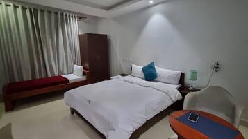 Une chambre d’hôtel comprenant un lit, une banquette, une armoire, une table de chevet et une lampe.
