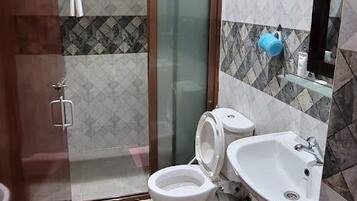 A bathroom with a shower, toilet, sink, and a mirror.