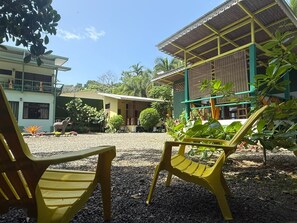 A courtyard with outdoor seating and a building with a covered area. - Casa Bocaracá · Moderna · 4 PAX · Aire Acondicionado (Playa Chiquita)