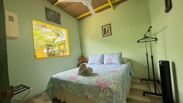 Een kamer met een bed, een plafondventilator, een raam met uitzicht, een radiator en een tv-meubel.