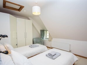 Quarto com duas camas, guarda-roupa, uma cadeira e um radiador.