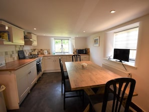 A kitchen with a dining table, chairs, a microwave, and a window with blinds. - 2 Bed in Dorchester (oc-dc025) (Chaldon Herring)