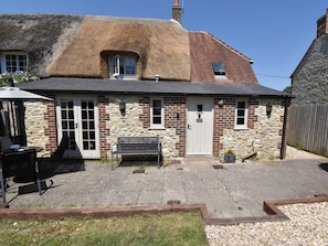 A stone and brick cottage with a thatched roof, a front door, and a bench outside. - 2 Bed in Dorchester (oc-dc025) (Chaldon Herring)
