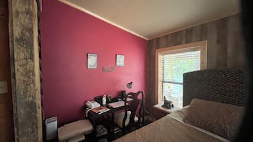 A room with a bed, a desk with a chair, a telephone, and a window with blinds.