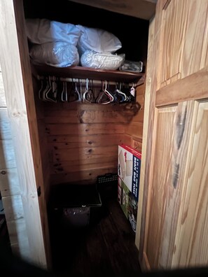 A wooden closet with hanging clothes and a storage box.
