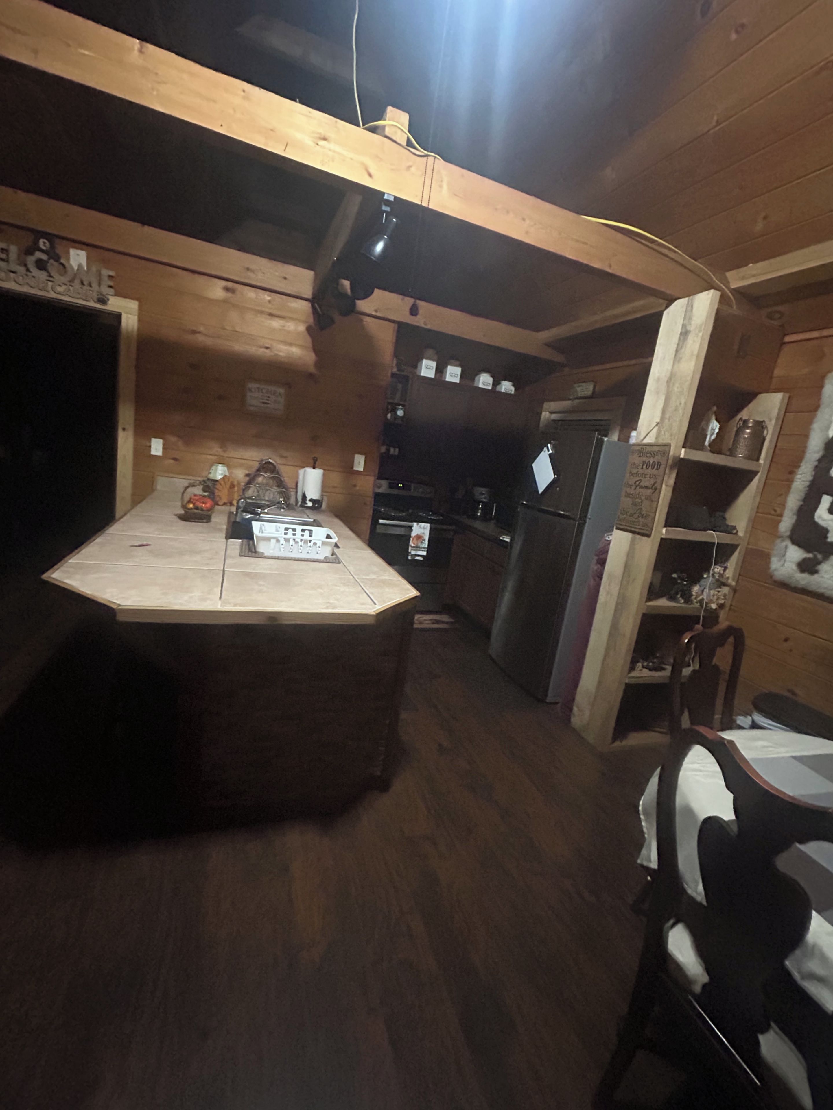 A wooden interior with a kitchen area, a dining table, and a chair.