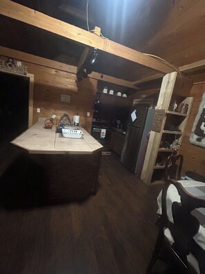 A wooden interior with a kitchen area, a dining table, and a chair.