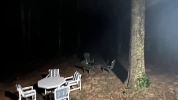 An outdoor seating area with a table and chairs, surrounded by trees.