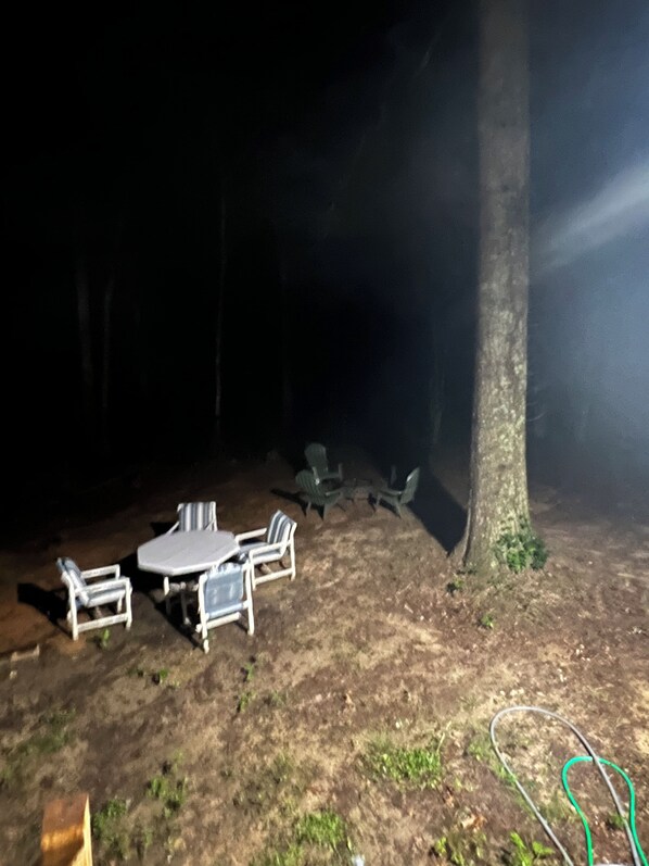 An outdoor seating area with a table and chairs, surrounded by trees.