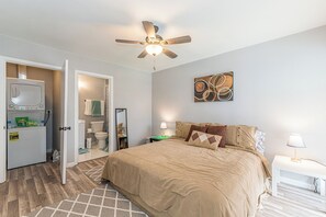 Un dormitorio con cama, mesita de noche, baño con inodoro, lavabo y espejo.