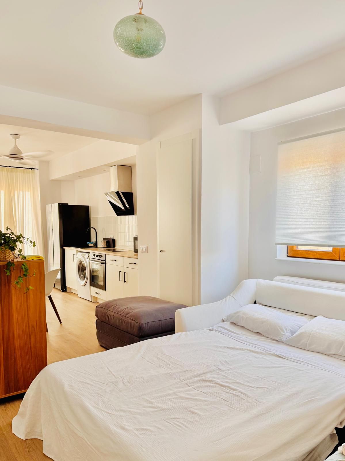 Un dormitorio moderno con una cama grande, una mesita de noche de madera y vistas a una zona de cocina.