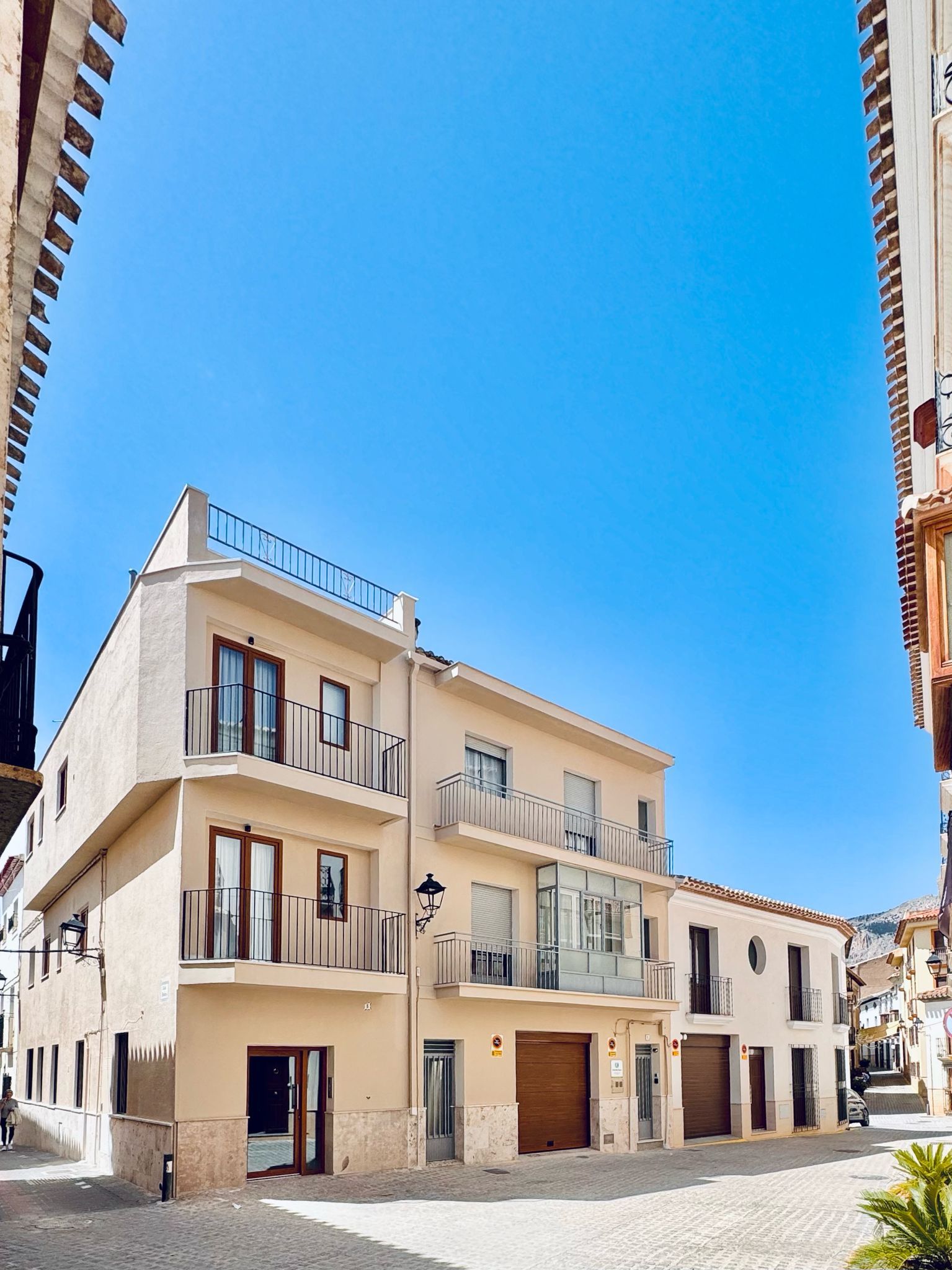 Un edificio de varios pisos con balcones, entrada principal y cielo despejado.