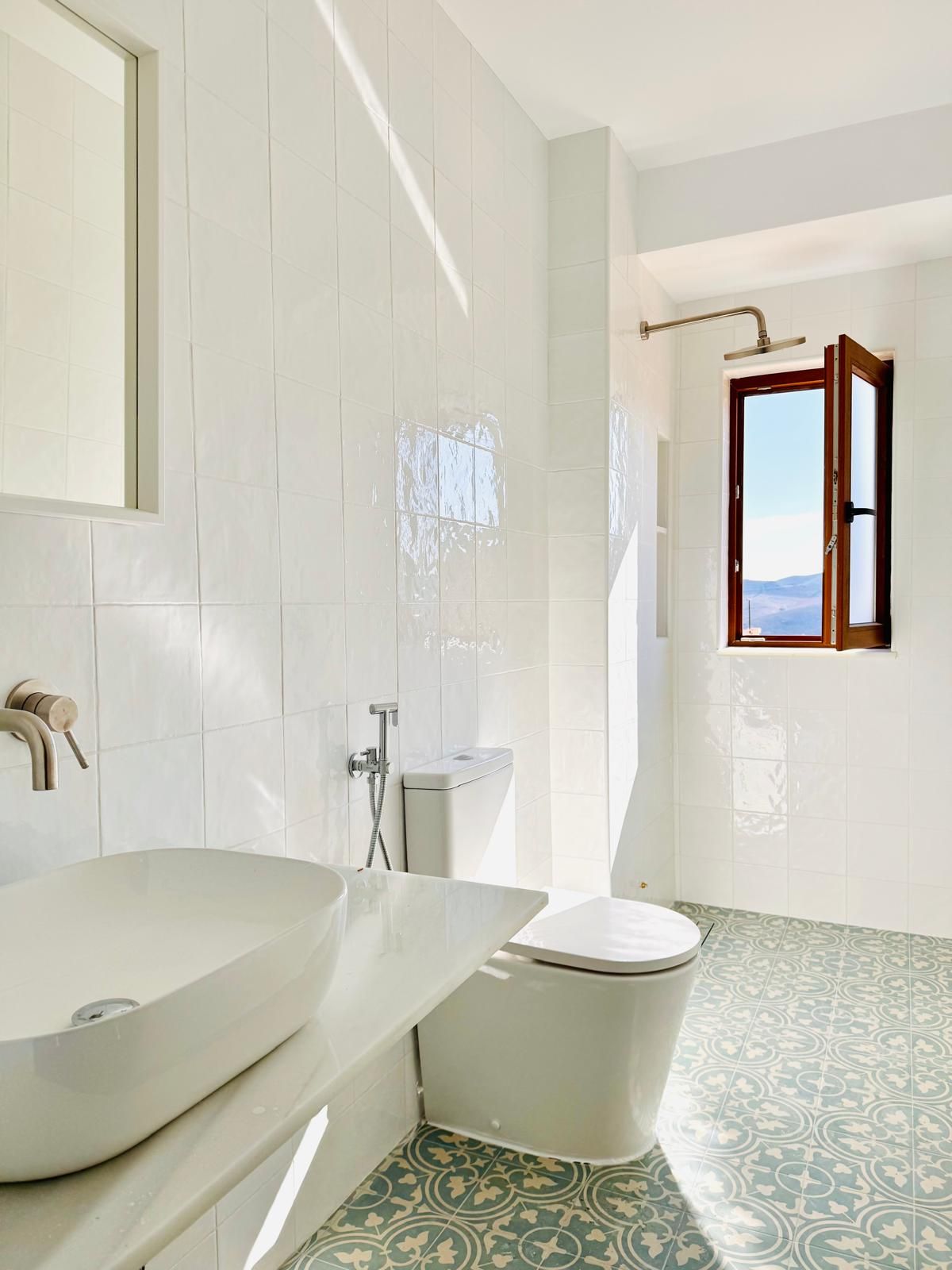 Un baño con un lavamanos grande de color blanco, un inodoro y una zona de ducha.