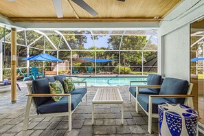 Ein überdachter Außenbereich mit Pool, Stühlen und Sonnenschirmen.