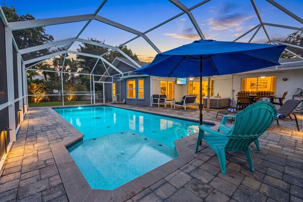 Ein Schwimmbecken mit überdachter Terrasse, Sitzgelegenheiten im Freien und einem Whirlpool.