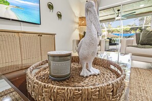 A room with a television, a decorative sculpture, a candle, and a wicker basket. - Tranquil Naples 4BR Retreat-Htd Pool-Koi Pond-Pets (Naples)
