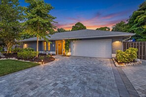 Ein Wohnhaus mit gepflasterter Auffahrt, Garage und einem angelegten Garten.
