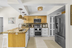 Een moderne keuken met een centraal eiland, roestvrijstalen apparatuur en houten keukenkastjes.