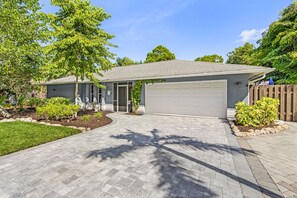Ein Wohnhaus mit Garage, gepflasterter Auffahrt und angelegtem Garten.