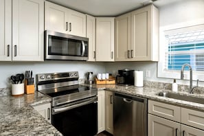 A modern kitchen with stainless steel appliances, white cabinetry, and a granite countertop. - Wilmington Family Home, Sleeps 6, Pets friendly, Minutes to Riverwalk (Wilmington)
