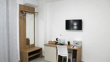 Ein kleines Zimmer mit einem Holztisch, einem weißen Stuhl, einem an der Wand befestigten Fernseher und einer kleinen Kommode.