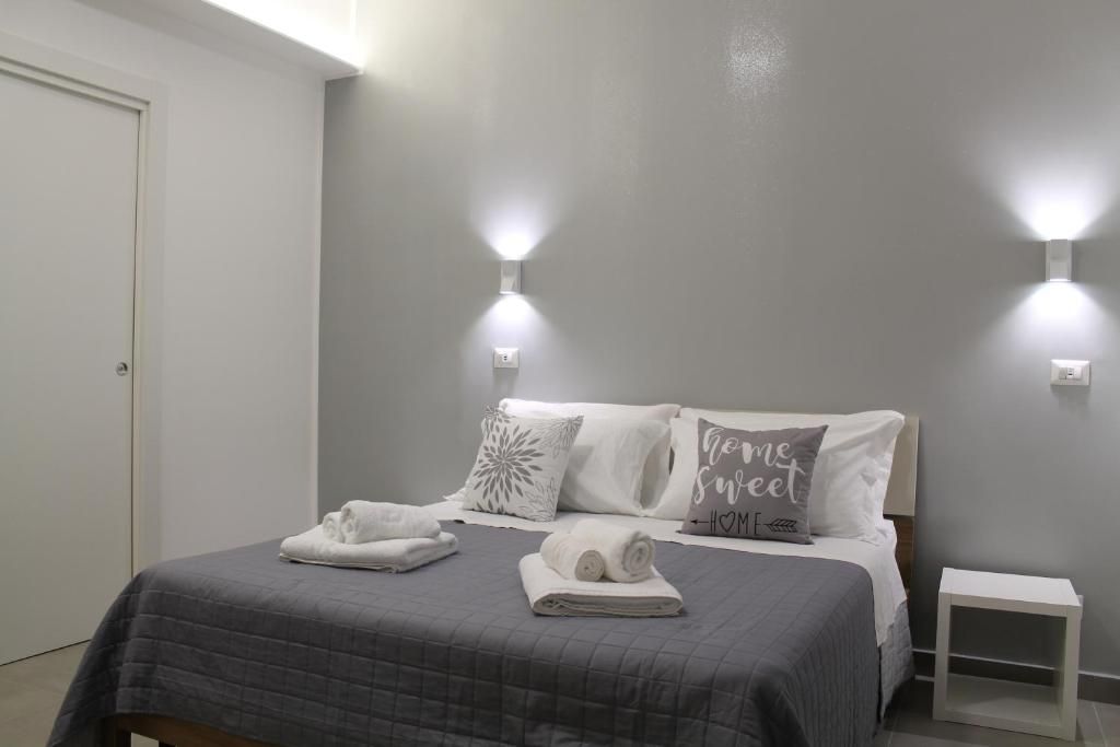 Un dormitorio con cama, dos luces en la pared, una mesita de noche y una puerta.