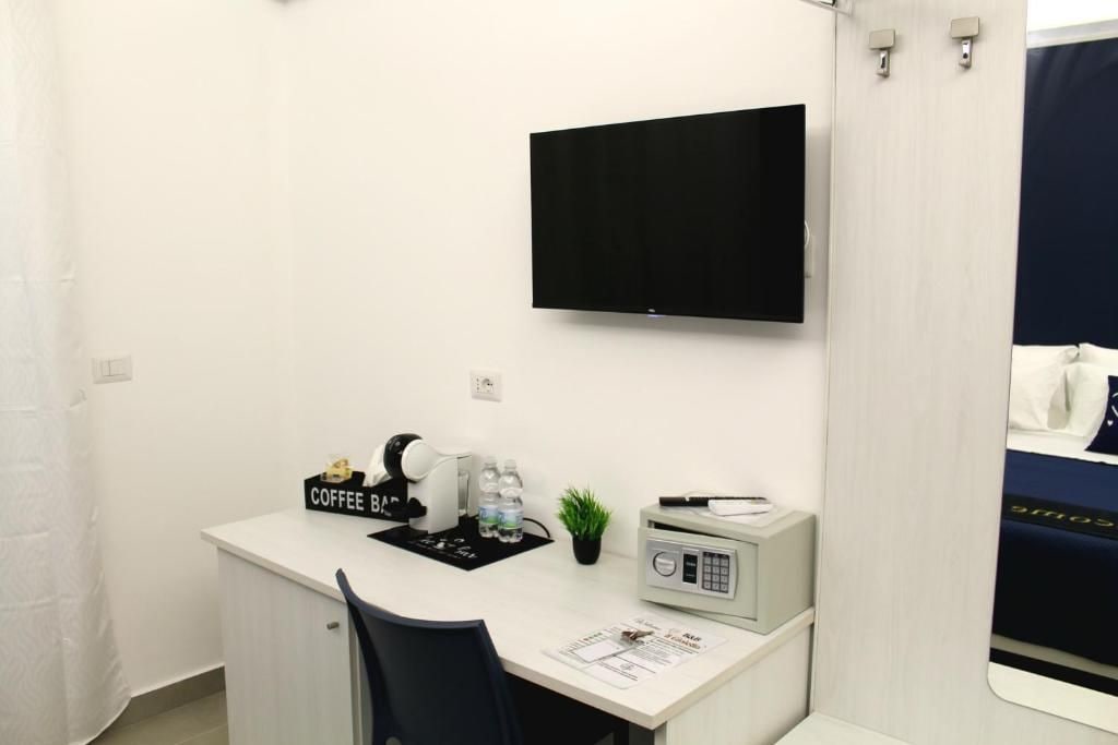 Una habitación de hotel con escritorio, cafetera, radio y cama con cubrecama azul.