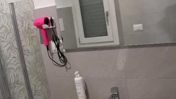 Une salle de bain avec un lavabo blanc, un miroir et une fenêtre située au-dessus du miroir.