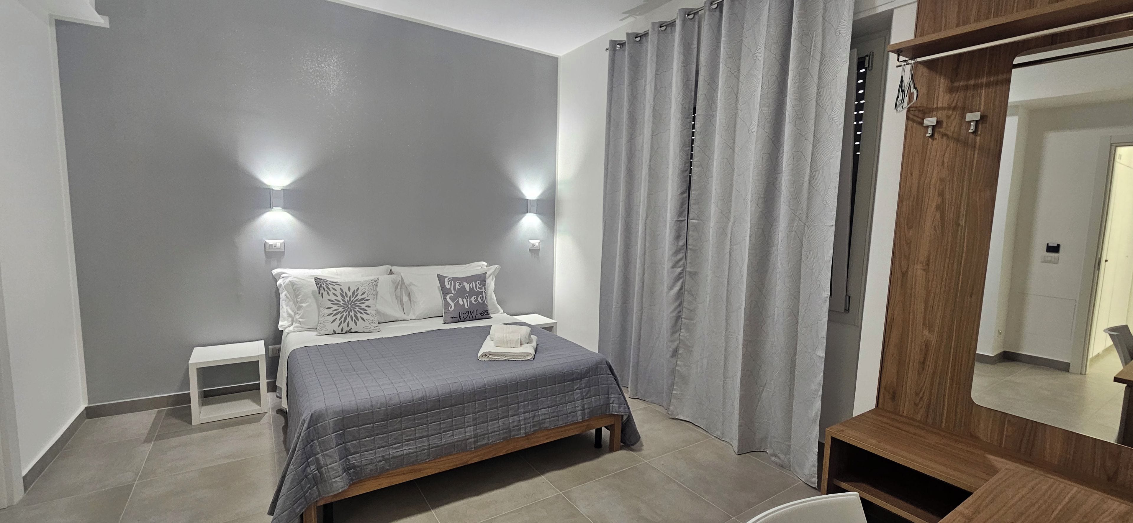 Una camera da letto con un letto, comodini, uno specchio e tende.