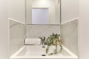 Ein Badezimmer mit einem weißen Waschbecken, einem Spiegel darüber und einem Handtuch an der Seite.