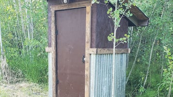 Un cobertizo de madera pequeño con puerta de metal corrugado y techo inclinado.