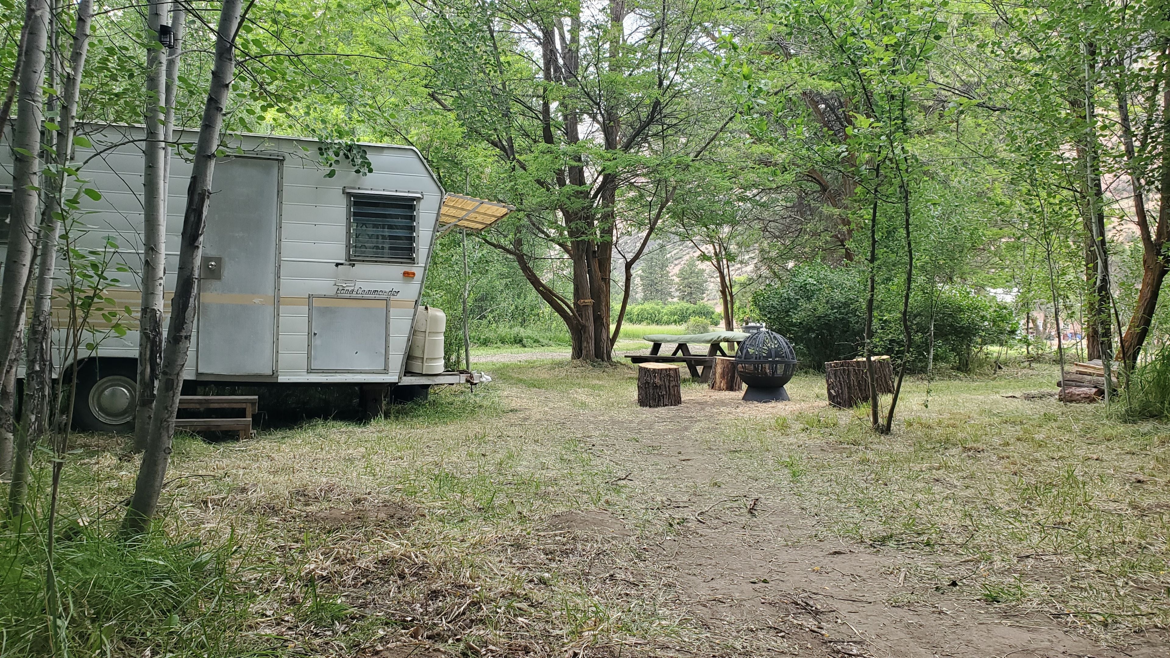 Un terrain de camping équipé d’une caravane, d’une table de pique-nique et d’un foyer.