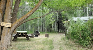 Un terrain de camping rustique avec un panneau en bois, une table de pique-nique et un foyer.