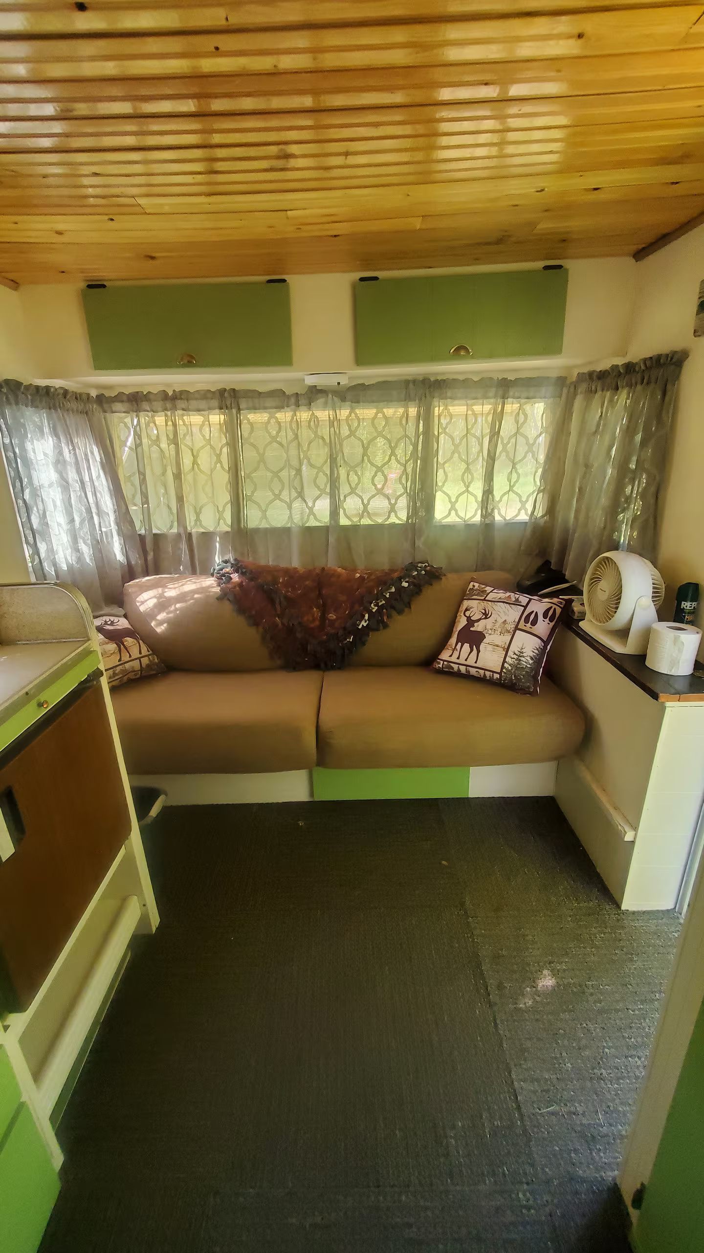 Un espace de vie compact comprenant un canapé, une petite table et un ventilateur.