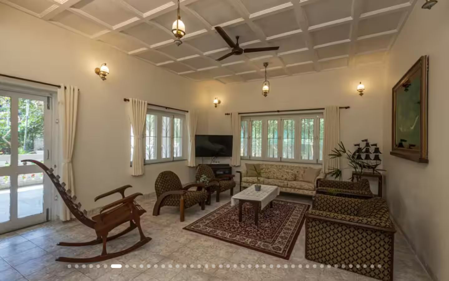 A spacious living room with a ceiling fan, a sofa, a coffee table, and a rocking chair.