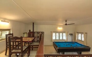 Una habitació amb taula de bitlles, taula de menjador amb cadires i ventilador de sostre.
